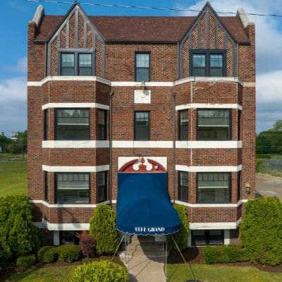 A Large Brick Building With Grass In Front Of A House
