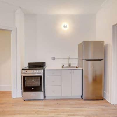 A Kitchen With A Stove Top Oven Sitting Inside Of A Hard Wood Floor